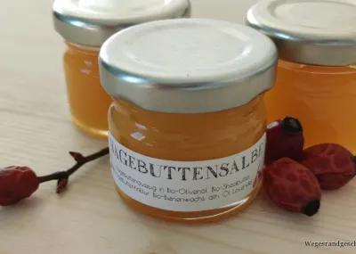 Gläser mit orangefarbener Hagebuttensalbe und Hagebutten