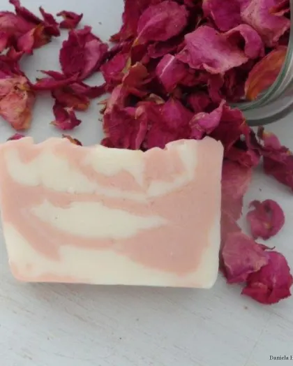 Marmorierte Palmarosaseife in Rosa und Weiß auf Rosenblüten